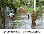 Small photo of A family wade through a flooded road to residence, at Kalgachia of Barpeta district of Assam, India on July 12, 2019.