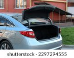 Grey Car with open trunk. Modern car with open empty trunk outdoors.