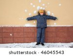 Small photo of boy kid is standing near wall with snowballs snow stains. Risky bombardment shooting of defenceless boy by snowballs near wall