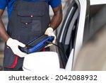 African American black people. Professional car mechanic repair service and checking car engine by Diagnostics Software computer. Expertise mechanic working in automobile repair garage. 