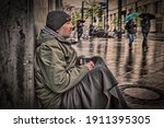 Homeless Man Sits On A Wall Of...