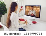 Happy woman looking at man on computer screen and giving toast on romantic virtual date. Couple in love raising glasses and drinking wine together, celebrating Saint Valentine's Day via video call