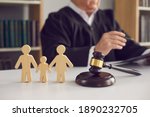 Gavel, sound block and small wooden figurines of husband, wife and kid on judge