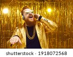 Happy man DJing at nightclub party. Guy in shiny jacket, headphones and cool sunglasses standing on disco club stage with golden background, mixing loud music, playing popular songs and having fun