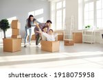 Family with children having fun in new home. Joyful first-time buyers with kids playing with boxes in living room. Real estate, residential mortgage, moving into dream house, happy future concept
