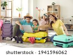 Happy excited family and daughter children buying payment for flight ticket booking hotel online using laptop with travel suitcase around at home living room. Holiday vacation traveling abroad concept