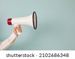 Close up of man hand hold loudspeaker advertise good sale deal or discount. Picture isolated on green studio background. Male with megaphone make announcement of promotion. Copy space.