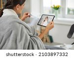 Small photo of Sick young woman who has high temperature is using digital tablet device, having online telemedicine consultation, holding thermometer, telling doctor about symptoms, asking for help and prescription