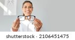 Small photo of Doctor giving you new prescription glasses. Happy optometrist showing modern good quality eyeglasses. Optometry, eyewear, eye health concept. Grey text copyspace banner background, closeup, close up