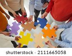 Small photo of Close up top view of diverse multiracial businesspeople hold jigsaw pieces connect puzzle seek for business solution in office. Employees or colleagues involved in teambuilding activity or training.
