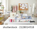 Empty fashion atelier of designer or seamstress with threads and sewing machine on table. No people in own stylish workshop of tailor or dressmaker. Clothing garment design. Style and dressmaking.