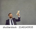 Small photo of Happy smiling man in suit, businessman or male employee, holding ascending graph chart arrow going up and ahead isolated on grey background. Success, career job skills boost, business growth metaphor