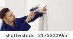 Small photo of Repair service worker uses screwdriver to fit screws and adjust wall mounted security camera. Young male technician installing CCTV surveillance cam for theft deterrence at home or in office building
