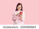 Small photo of Online connectivity, working or socializing remotely. Joyful young woman on pastel pink background swipes and scrolls on screen of mobile phone. Smiling woman smiling looking at smartphone screen.