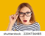 Small photo of Funny surprised student girl. Young blonde woman in glasses sees something unbelievable and looks at camera with shocked, stunned, astounded, impressed face expression. Closeup, close up headshot
