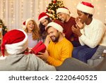 Small photo of Smiling multiracial friends exchange Christmas gifts at celebration at home together. Happy diverse international group of young people greet congratulate with New Year give presents.