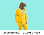 Small photo of Portrait of guy in funky costume with dinosaur face posing in studio. Man in stylish bright yellow suit and funny ugly T Rex mask standing with hand in pocket on blue background. Crazy fashion concept