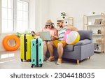 Small photo of Family couple prepared for holiday travel sitting on couch and looking at laptop with shocked face expression reading information about service problems, delayed flight or canceled hotel room booking