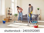 Small photo of Young happy couple engages in home cleaning, with a vacuum and mop. They demonstrate togetherness and joyous teamwork, transforming household chores into moments of family connection.