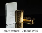 Gold and silver bars of various weights on a black mirror background. Selective focus.