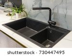 Black kitchen sink and Tap water in the kitchen. The interior of the kitchen room of the apartment. Built-In Appliances. Kitchen Appliance. Domestic Appliances