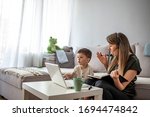 Small photo of Mother working from home with kid. Children make noise and disturb woman at work. Homeschooling and freelance job. Moms Can Balance Work and Family. Multitasking mother working from home.