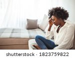 Small photo of Close up african female sit on couch feels unhappy desperate thinking about personal difficulties mental health problems, 30s sad woman need psychological support goes through divorce break up concept