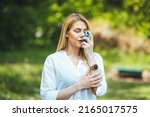 Small photo of An asthmatic girl who takes an inhaler and has an asthma attack. A young woman has an asthma attack. She's holding an inhaler. She walks outside and has a problem with asthma