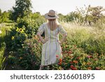 Woman standing in flower garden. Female florist relaxing and enjoying view at blooming floral farm in summer