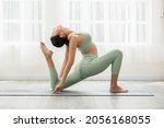 Side view of Asian woman wearing green sportwear doing Yoga exercise,Yoga One Legged King Pigeon pose or Eka Pada Rajakapotasana,Calm of healthy young woman breathing and meditation with yoga at home
