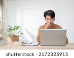 Small photo of Freelancer Asian man looking at computer laptop screen concentrate and thinking with him job. Serious business man working at home having problem with job thinking to solve problem.