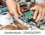 Small photo of Technician remove a hard disk drive from the CCTV DVR recorder case, to install a new hard drive and upgrading to a Solid State for backup CCTV camera , electrical work and cctv concept