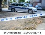 Small photo of Police patrol car and police tape marking off a crime scene on a street. Barricade tape lettering: Stop, police".
