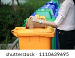a woman dump a plastic bottle garbage to yellow recycle bin in a park