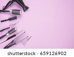 Hairdresser tools on lilac pink background with copy space in center, top view, flat lay. Comb, scissors, thinning scissors, hair clip, hairdryer, curling iron