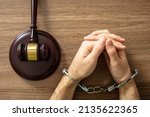 Small photo of Handcuffed Convict, Law offender and Justice. Court sentence Prison. Handcuff locked and judge gavel on a wooden table, top view.
