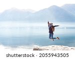Young woman jumping at nature, winter sea beach. Traveler enjoying traveling