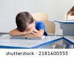 School child sleeping on boring lesson. Tired pupil learning to read book. Sleepy kid sitting at desk in classroom in elementary college. Primary student back to school in early morning