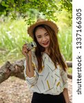 Small photo of Women tourists women white skin lovely brown hair wearing a basketry hat wear white shirt wearing black pants in hand have a camera traipse photograph nature.