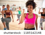 Pretty female instructor with headset in fitness class exercise with group 