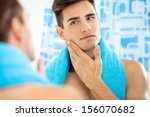 Young handsome man touching his smooth face after shaving