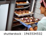 A young small business female owner fills the closet with delicious handmade donuts in a pleasant atmosphere in a candy workshop. Pastry, dessert, sweet, making