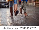 Small photo of Close-up of a young couple and their legs how walking on the rain in the city in a hurry manner. Walk, rain, city, relationship