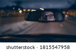 Small photo of Driver's face is reflected in a rear view mirror, night shot, violet color, bokeh light. Tired concentrated driver in eyeglasses is reflected in a mirror in car, night road shot driving all night
