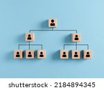 Company hierarchical organizational chart of wooden cubes on blue background. Human resources management and business concept