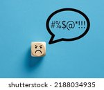 Small photo of Angry face icon on a wooden cube with swearing or swearwords icons in a speech bubble. Swearing and bad language concept.