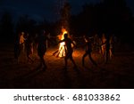 People dance around the campfire. People dance around the fire at night.