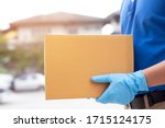 Small photo of parcel delivery man wear protective gloves blue, protect Hygiene germs and bacteria of a package through a service send to home. hand holding consign and submission customer accepting a of box.