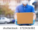 Small photo of parcel delivery man wear protective gloves blue and mask, protect Hygiene germ and bacteria of a package through a service send to home. hand holding consign and submission customer accepting a of box