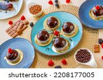 Chocolate round cake with raspberry set on a blue plate on a light background.Berry dessert.Delicate airy cake souffle.Appetizing cupcakes and pastries.